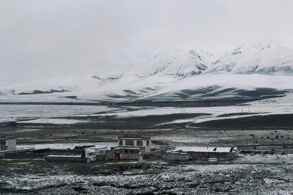 Häuser und schneebedeckte Berge in Tibet