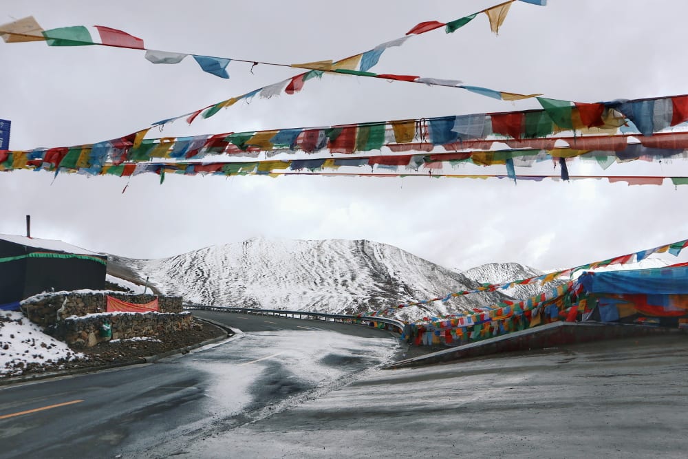 Tibetische Gebetsflaggen mit schneebedecktem Berg